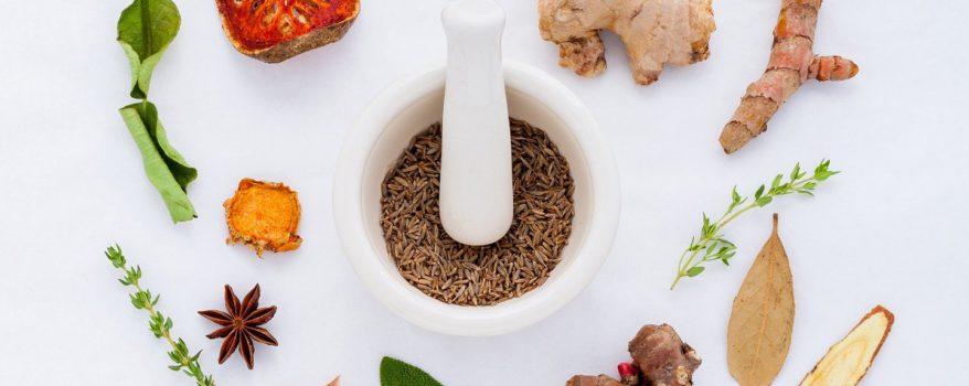 Herbs and spices circling a pestle and morter