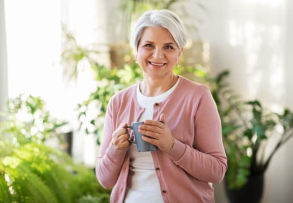 Elderly woman in kitchen enjoying a cup of tea