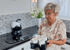 elderly woman bringing tea in her Muggi Cup Holder