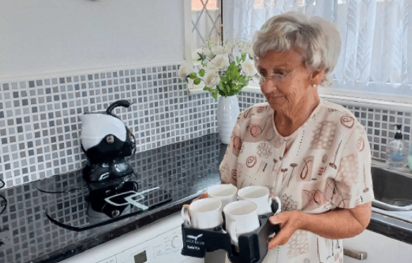 elderly woman bringing tea in her Muggi Cup Holder