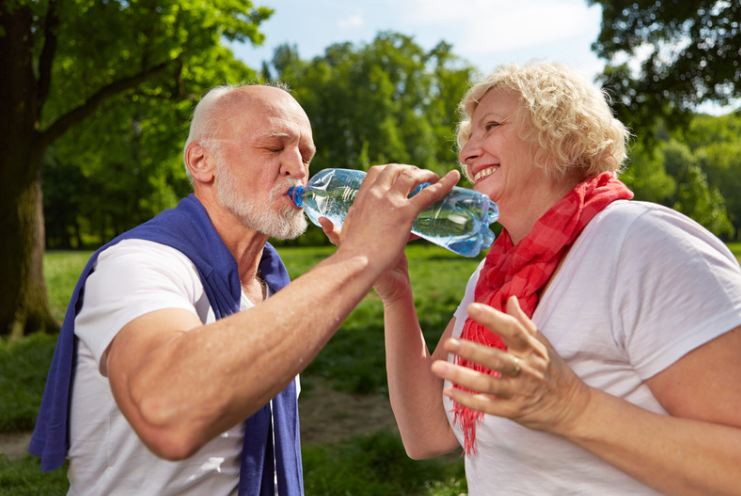 Elderly couple drinking water in the summer sun