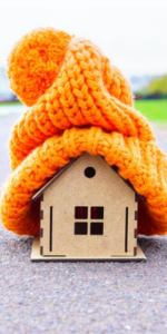 Little wodden house on the road with a large orange wooly hat