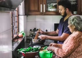 Adult son helping his elderly mother prepare dinner in the kitchen