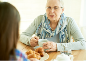 Daughter talking to her elderly mother over tea