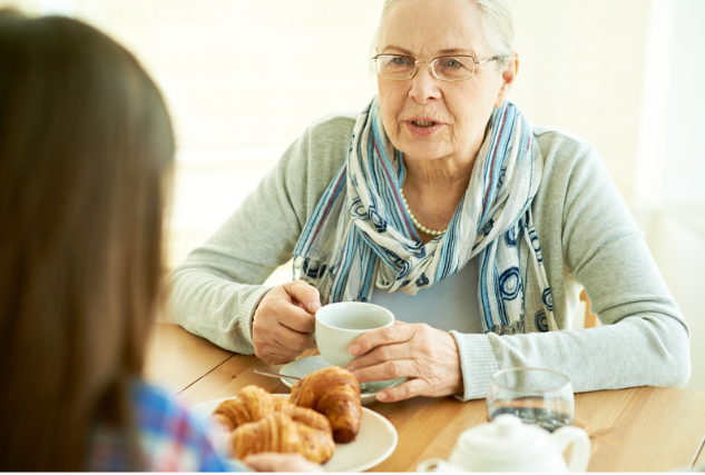 Daughter talking to her elderly mother over tea