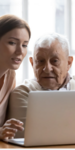 Adult daughter showing elderly father how to use a laptop