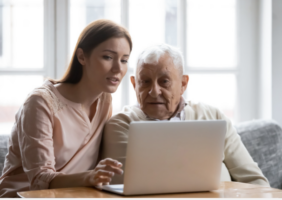 Adult daughter showing elderly father how to use a laptop