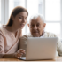 Adult daughter showing elderly father how to use a laptop