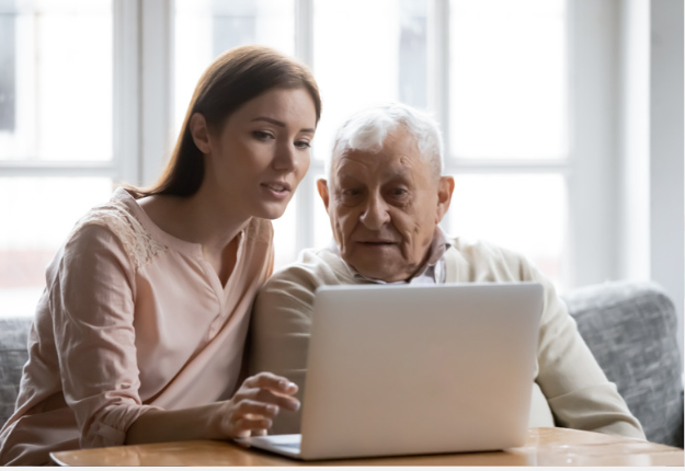 Adult daughter showing elderly father how to use a laptop